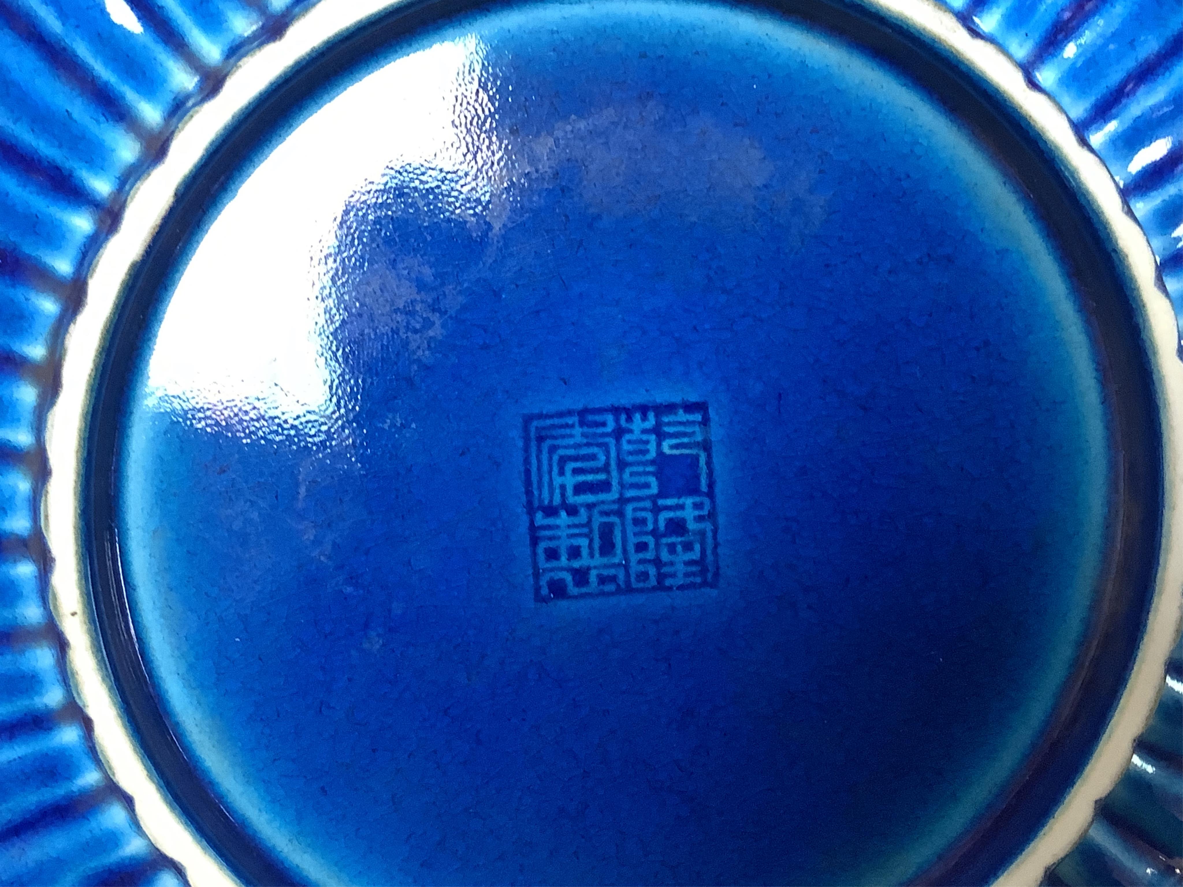 A Chinese blue glazed cylindrical brush pot, Kangxi mark but later, a similar saucer, Qianlong mark but later and a terracotta jug, 21cm